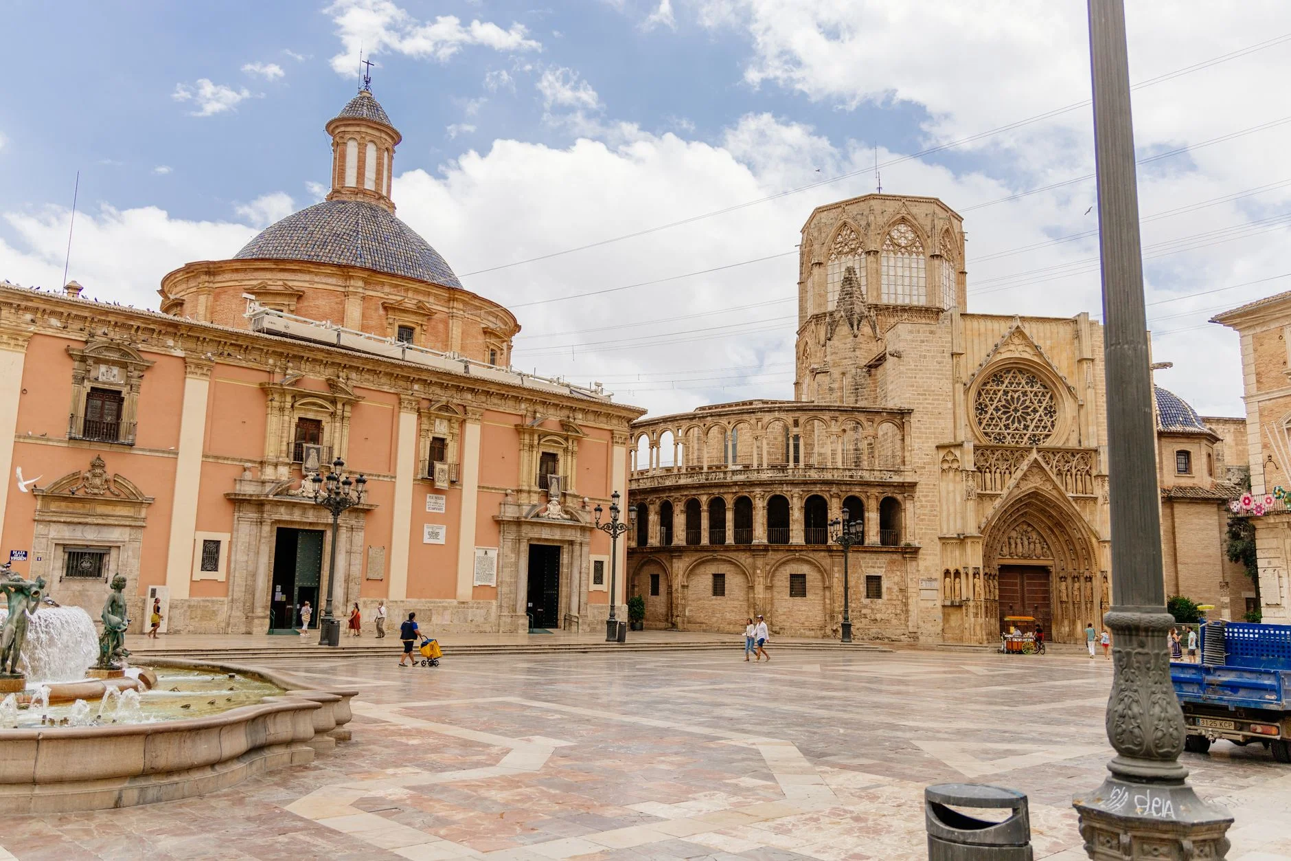 A photorealistic, professional photography, 8K image of a traveler respectfully engaging in a local tradition or custom, perhaps sharing a meal or participating in a small community event, cultural exchange, cinematic lighting, sharp focus, depth of field, shot on a high-end DSLR. Beautiful view of Valencia Cathedral and Plaza de la Virgen with historical architecture in Spain. — Foto: Tiago Alvar / Pexels