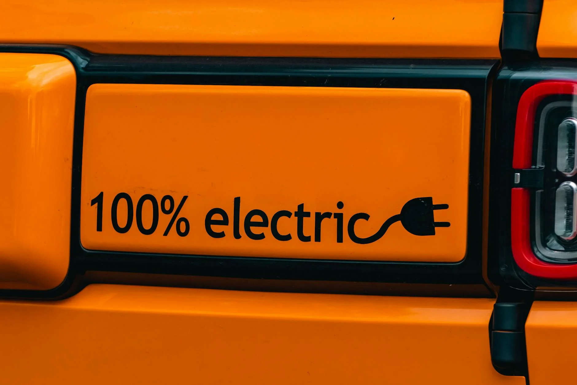 A photorealistic image showing an interactive display at a sustainable event, illustrating real-time energy consumption and the impact of participant actions, with smiling people looking at the screen. Professional photography, 8K, cinematic lighting, sharp focus on the display and faces, depth of field blurring the background, shot on a high-end DSLR. Vibrant orange electric vehicle with a '100% electric' emblem, showcasing eco-friendly transportation. — Foto: Mad Knoxx Deluxe / Pexels