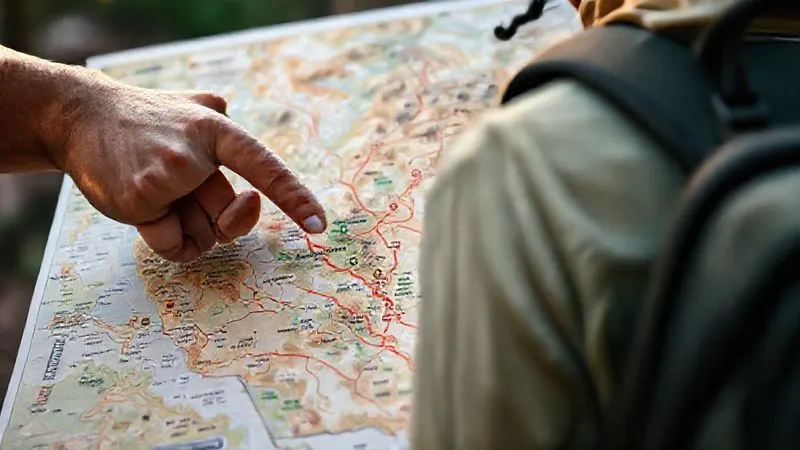 A photorealistic image of a detailed map of a national park, with a hand (respectful, clean nails) pointing to a designated campsite. The map highlights sustainable trails and no-go zones. Cinematic lighting, sharp focus on the map details, depth of field blurring a backpack in the background. 8K hyper-detailed, professional photography, shot on a high-end DSLR. A photorealistic image of a detailed map of a national park, with a hand (respectful, clean nails) pointing to a designated campsite. The map highlights sustainable trails and no-go zones. Cinematic lighting, sharp focus on the map details, depth of field blurring a backpack in the background. 8K hyper-detailed, professional photography, shot on a high-end DSLR.