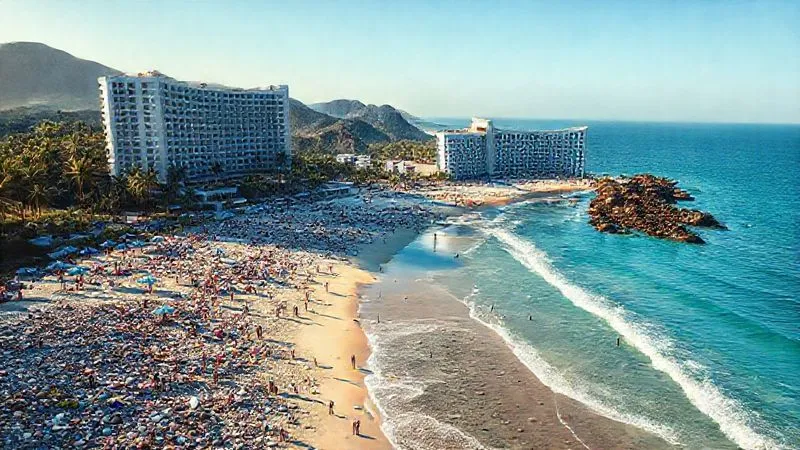 A photorealistic aerial shot of a beautiful, previously pristine beach now visibly crowded with tourists, plastic waste washing ashore, and large, sprawling hotel complexes dominating the coastline. The lighting is harsh, emphasizing the environmental degradation. Professional photography, 8K, cinematic lighting, sharp focus, depth of field, shot on a high-end DSLR. A photorealistic aerial shot of a beautiful, previously pristine beach now visibly crowded with tourists, plastic waste washing ashore, and large, sprawling hotel complexes dominating the coastline. The lighting is harsh, emphasizing the environmental degradation. Professional photography, 8K, cinematic lighting, sharp focus, depth of field, shot on a high-end DSLR.