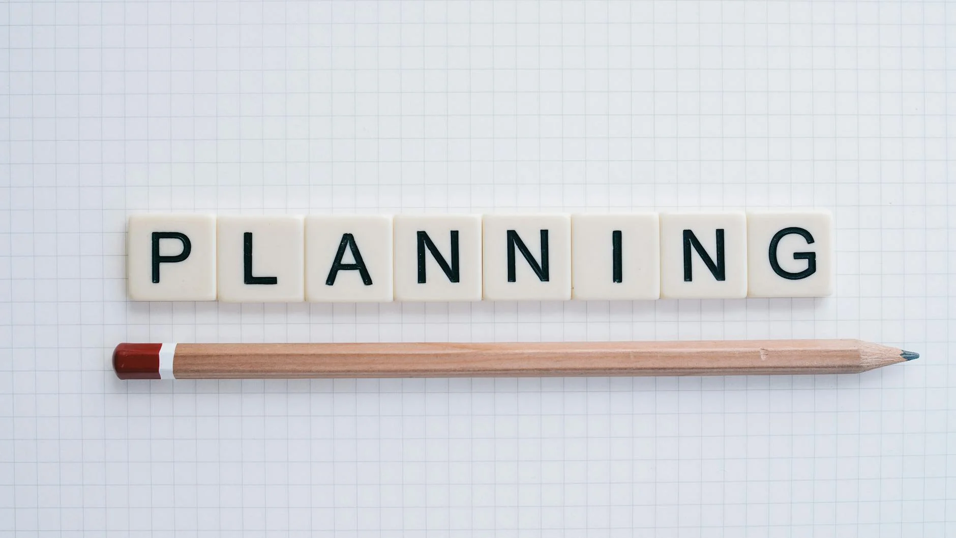 A photorealistic image of a person sitting thoughtfully by a window, journaling, with a soft blur of a distant landscape through the glass, symbolizing introspection and the start of a meaningful journey. Cinematic lighting, sharp focus on the journal, 8K hyper-detailed. Overhead shot of letter tiles spelling 'planning' with a pencil on graph paper. — Foto: Kathy Jones / Pexels